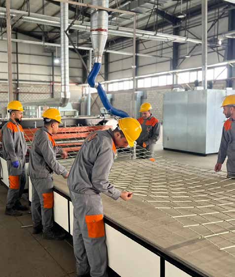 Workers laying fiberglass mesh on production table